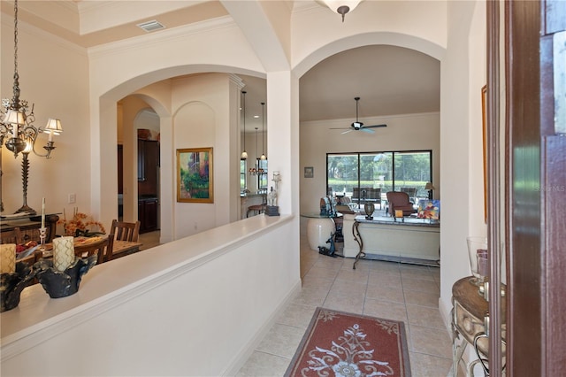 tiled entryway with ceiling fan with notable chandelier and crown molding