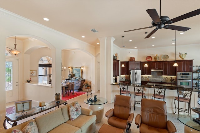 tiled living room with ceiling fan, crown molding, and decorative columns