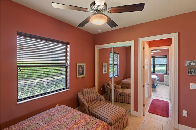 tiled bedroom featuring ceiling fan and a closet