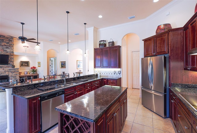 kitchen featuring sink, a center island, hanging light fixtures, dark stone countertops, and appliances with stainless steel finishes