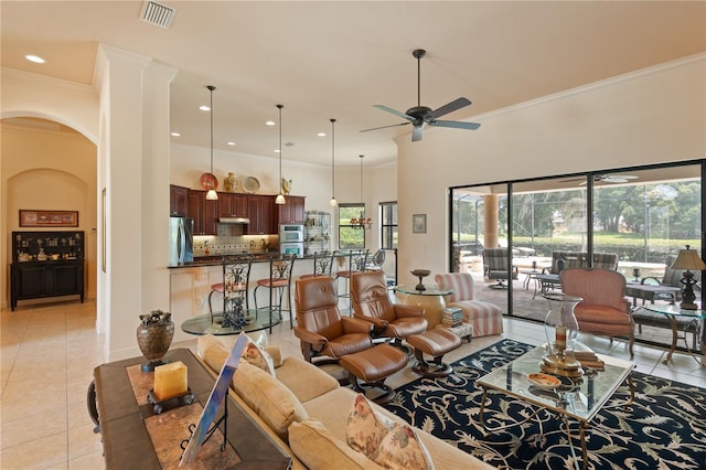 living room featuring light tile patterned floors, a towering ceiling, ceiling fan, and crown molding