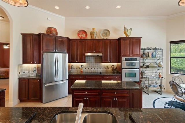 kitchen with dark stone countertops, sink, light tile patterned floors, and appliances with stainless steel finishes