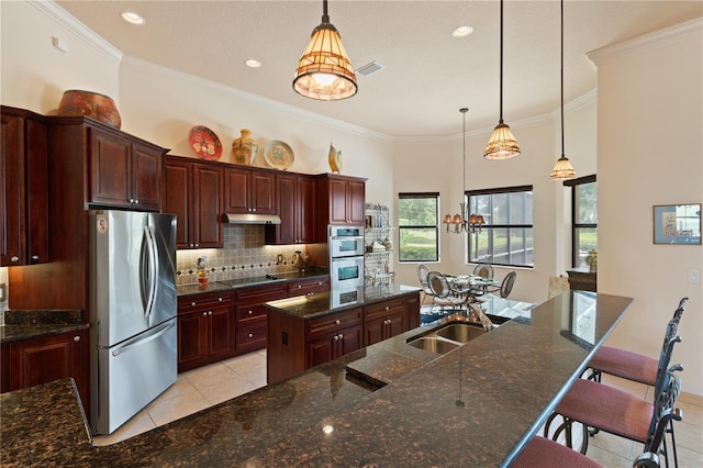 kitchen featuring a kitchen breakfast bar, a large island, decorative light fixtures, and appliances with stainless steel finishes