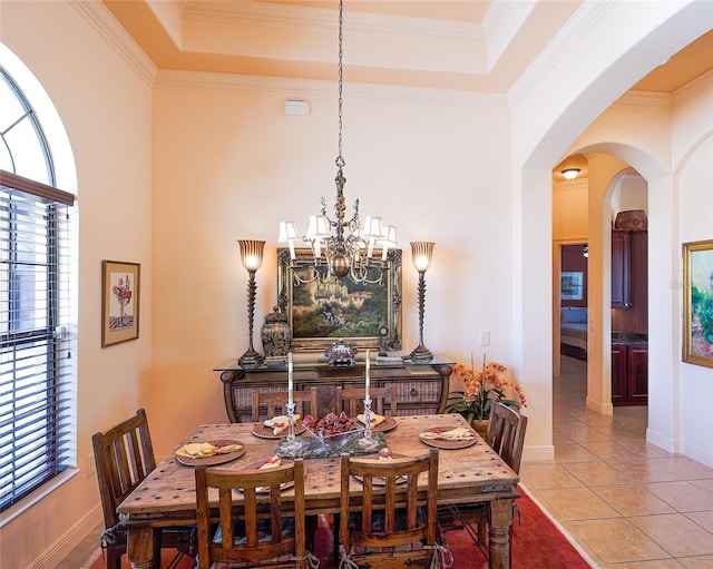 dining space with a raised ceiling, tile patterned floors, a notable chandelier, and crown molding