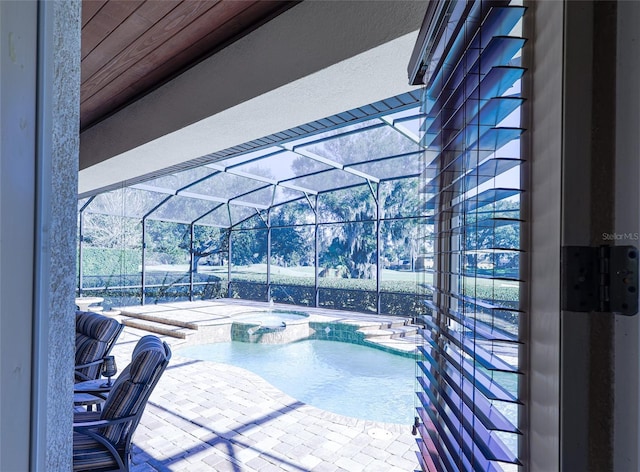 view of swimming pool featuring glass enclosure, an in ground hot tub, and a patio