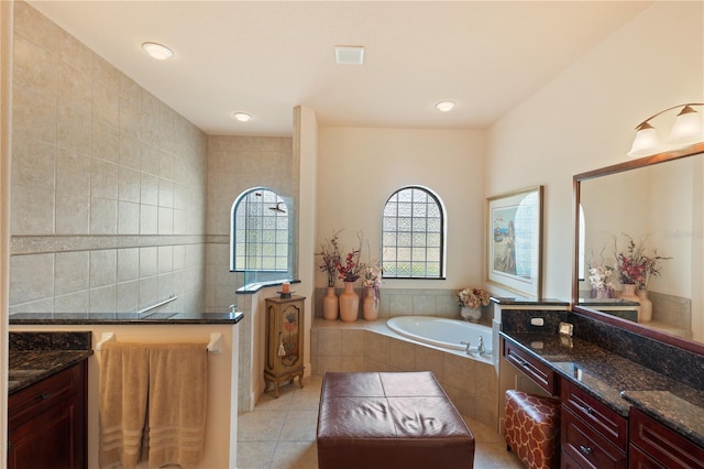 bathroom with tile patterned floors, tiled tub, vanity, and tile walls