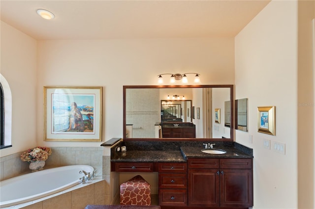 bathroom with vanity and tiled tub