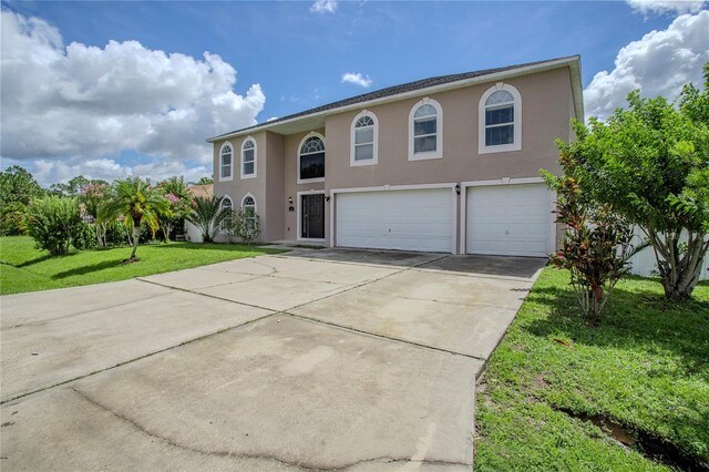 view of front facade with a front yard, concrete driveway, an attached garage, and stucco siding