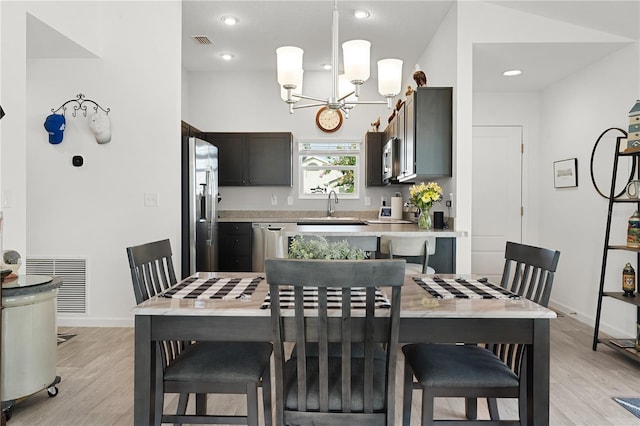 dining area with a notable chandelier, light wood-type flooring, and sink