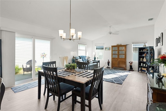 dining area with light hardwood / wood-style flooring, ceiling fan with notable chandelier, and vaulted ceiling