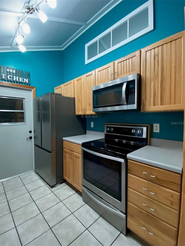 kitchen featuring appliances with stainless steel finishes, ornamental molding, vaulted ceiling, and light tile patterned floors