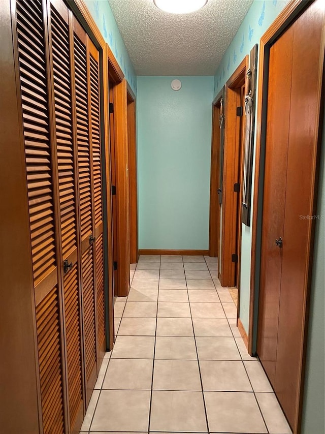 corridor featuring a textured ceiling and light tile patterned floors