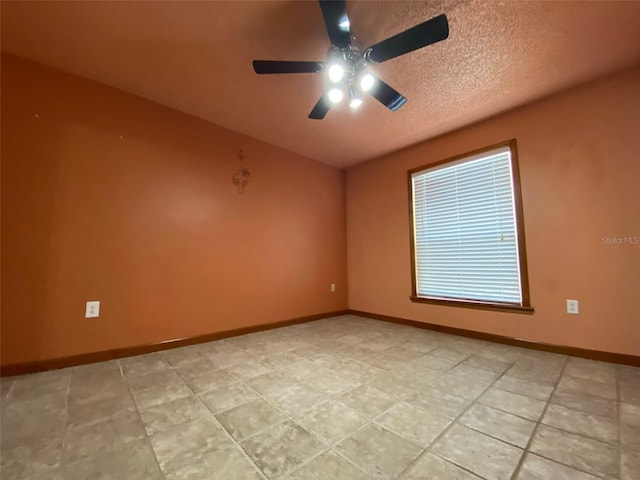 tiled spare room featuring a textured ceiling and ceiling fan