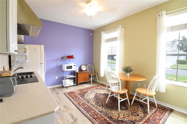 dining space with ceiling fan, light wood-type flooring, and sink