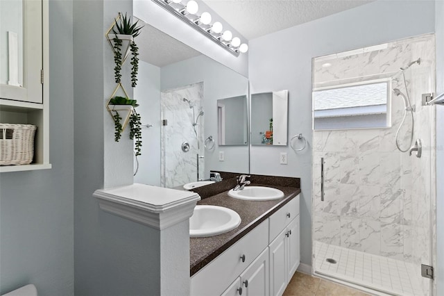 bathroom featuring walk in shower, a textured ceiling, vanity, and tile patterned flooring