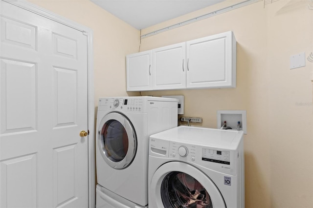 laundry area with separate washer and dryer and cabinets