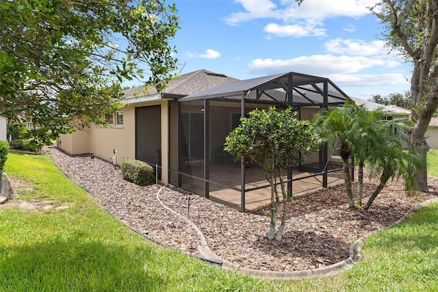 back of house with a yard and glass enclosure