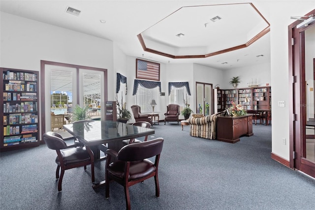 dining area with a raised ceiling and dark colored carpet