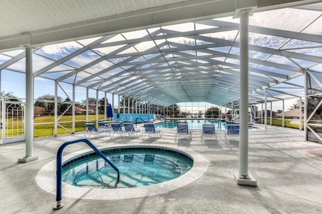 view of swimming pool featuring glass enclosure, an in ground hot tub, and a patio