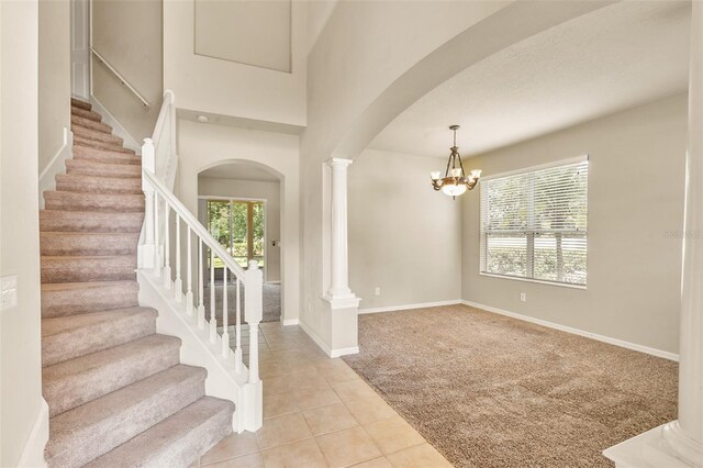 tiled foyer with a chandelier and decorative columns