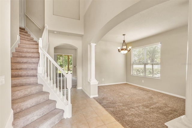 carpeted foyer entrance with ornate columns and an inviting chandelier