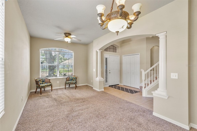 foyer with ceiling fan with notable chandelier, decorative columns, and light carpet