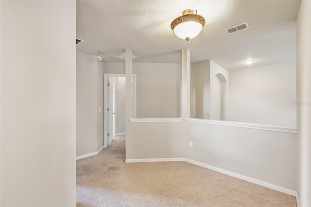 unfurnished room featuring a textured ceiling and light colored carpet