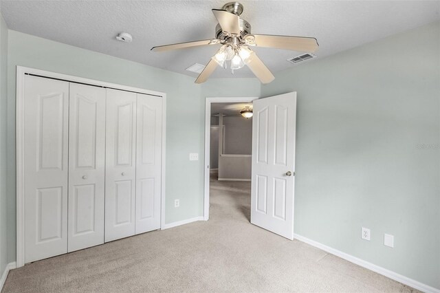 unfurnished bedroom featuring ceiling fan, a closet, and light carpet