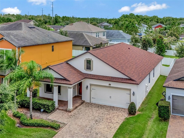 view of front of home with a garage, a residential view, decorative driveway, and stucco siding