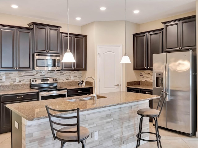 kitchen with sink, appliances with stainless steel finishes, pendant lighting, and an island with sink