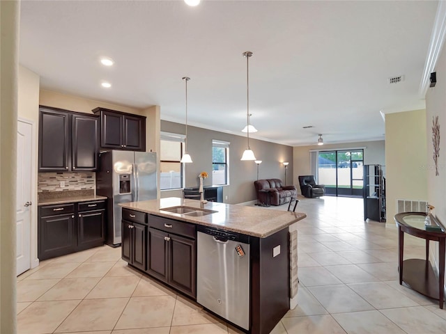 kitchen with an island with sink, appliances with stainless steel finishes, open floor plan, hanging light fixtures, and a sink