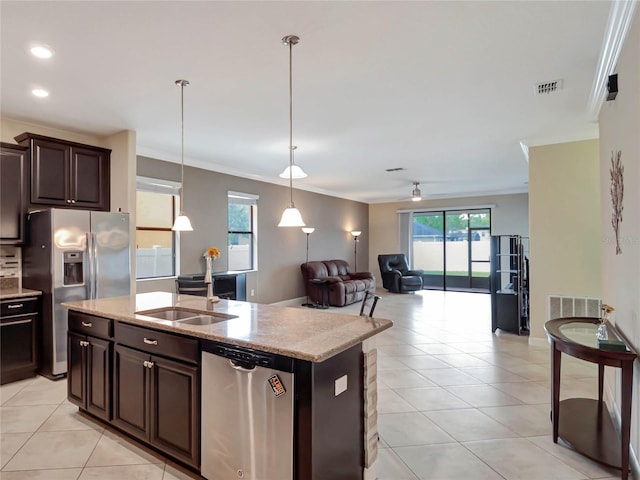 kitchen featuring dark brown cabinetry, stainless steel appliances, a sink, open floor plan, and an island with sink