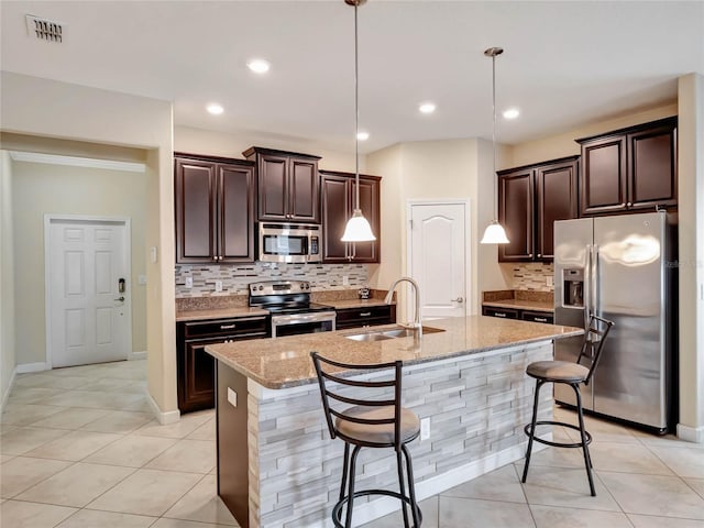 kitchen featuring a kitchen bar, a kitchen island with sink, stainless steel appliances, and a sink