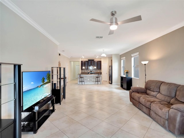 living room with ceiling fan, ornamental molding, and light tile patterned floors