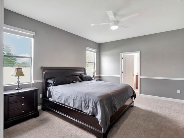 bedroom featuring light carpet, ceiling fan, and connected bathroom