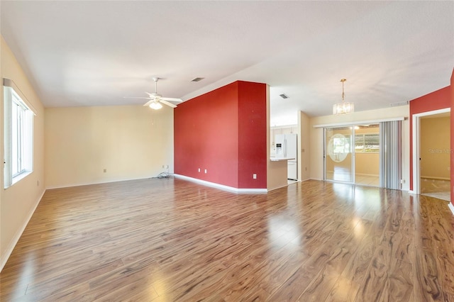 unfurnished living room with hardwood / wood-style floors, vaulted ceiling, and ceiling fan with notable chandelier