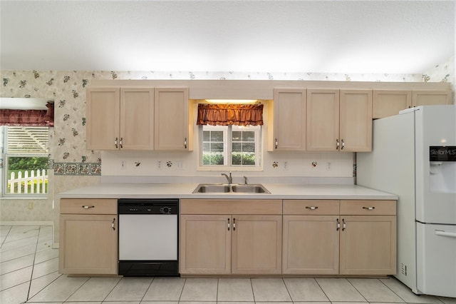 kitchen with sink, white appliances, light brown cabinets, and a wealth of natural light