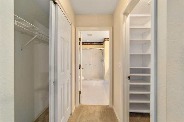 corridor featuring built in shelves and light colored carpet