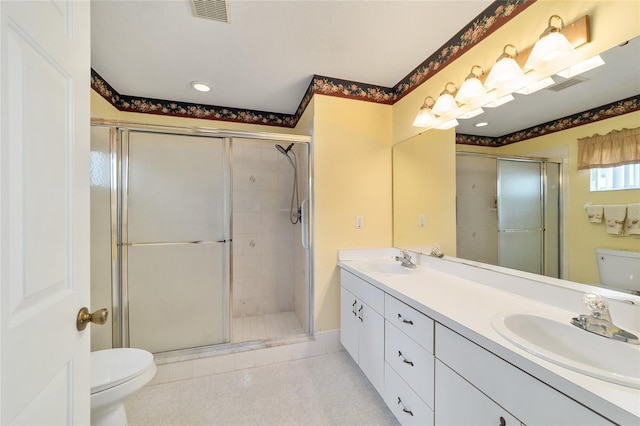 bathroom with toilet, vanity, and a shower with shower door