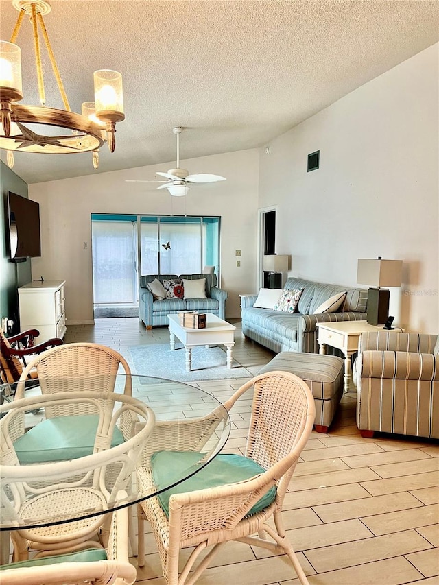 dining area featuring ceiling fan, light wood-type flooring, vaulted ceiling, and a textured ceiling