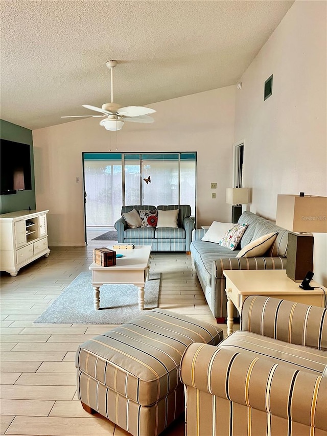 living room with ceiling fan, light wood-type flooring, a textured ceiling, and vaulted ceiling