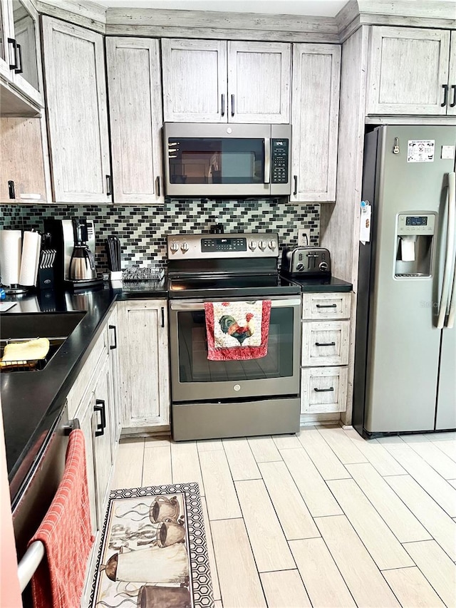 kitchen with gray cabinetry, appliances with stainless steel finishes, light hardwood / wood-style floors, and backsplash