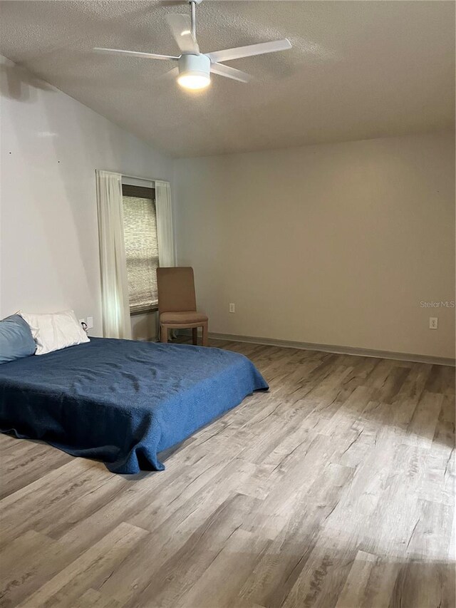 bedroom with hardwood / wood-style floors, a textured ceiling, and ceiling fan