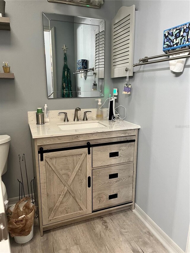 bathroom with vanity, toilet, and hardwood / wood-style floors