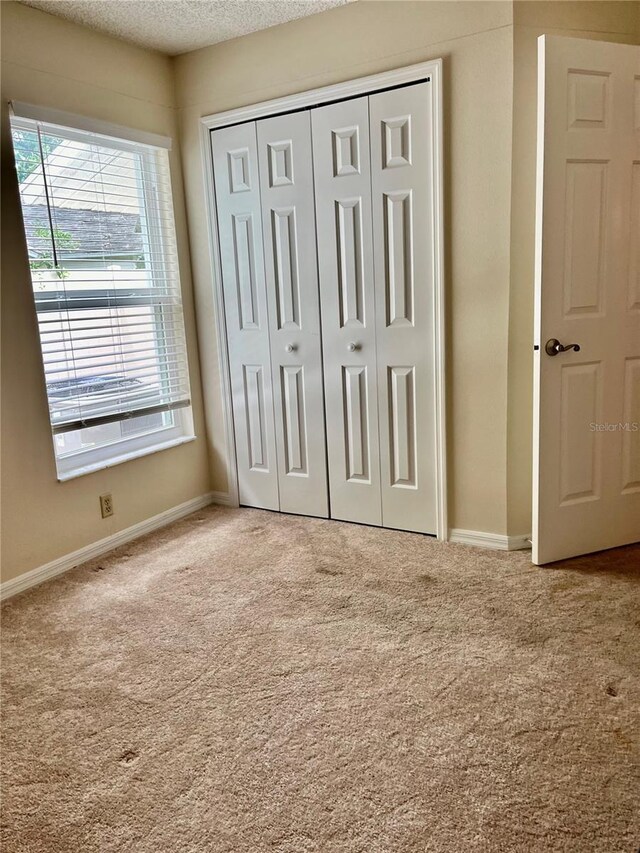 unfurnished bedroom featuring a textured ceiling, a closet, and carpet floors