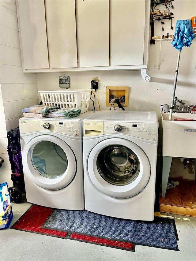 clothes washing area featuring cabinets and washer and dryer