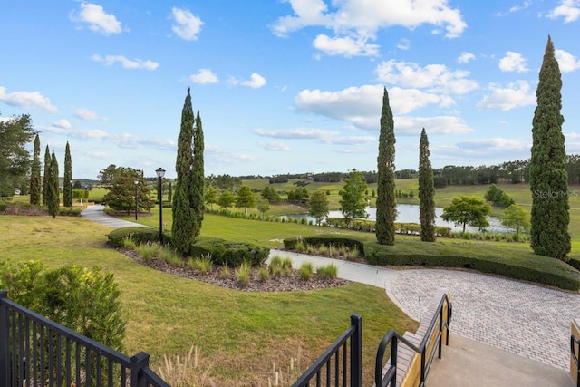 surrounding community with a water view and a lawn