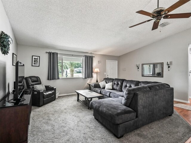 carpeted living room with ceiling fan, a textured ceiling, and lofted ceiling