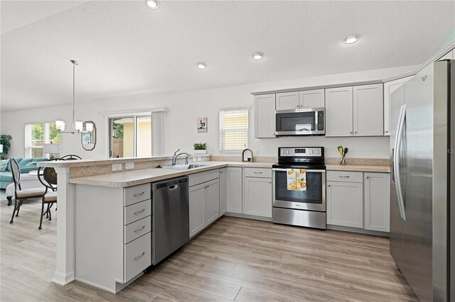 kitchen featuring a wealth of natural light, appliances with stainless steel finishes, hanging light fixtures, and light wood-type flooring