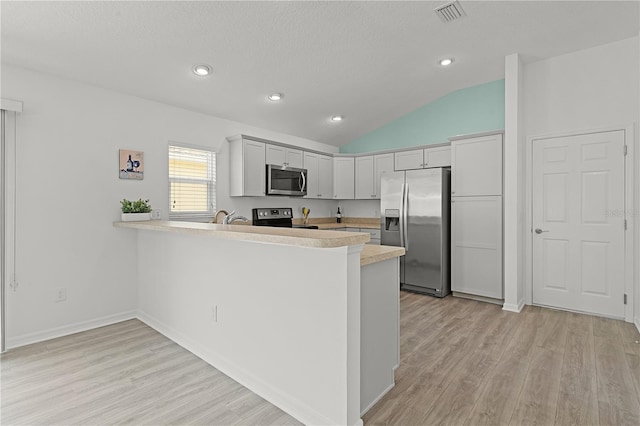 kitchen with lofted ceiling, kitchen peninsula, stainless steel appliances, and light wood-type flooring